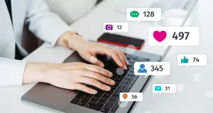 Hands typing on laptop with social media engagement icons—enhancing customer engagement through targeted social media campaigns.