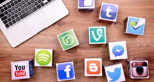 Social media platform icons on paper cubes next to laptop, representing digital marketing and engagement strategies