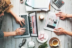 Marketing team planning early campaigns on laptop and tablet to boost landscaping services and lawn care advertising strategies."